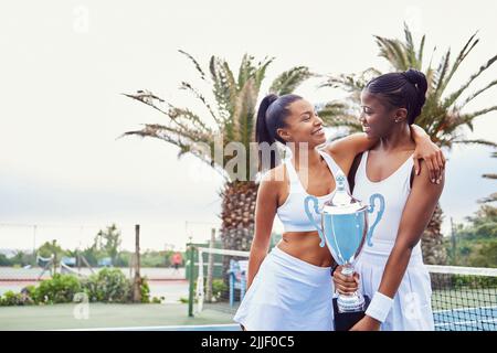 Champions spielen weiter, bis sie es richtig machen. Zwei junge Frauen feiern einen Sieg auf einem Tennisplatz. Stockfoto