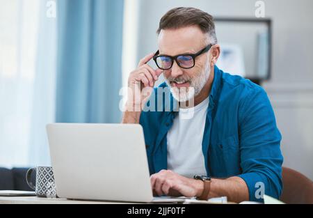 Das Geschäft boomt: Ein Geschäftsmann, der von zu Hause aus mit seinem Laptop arbeitet. Stockfoto