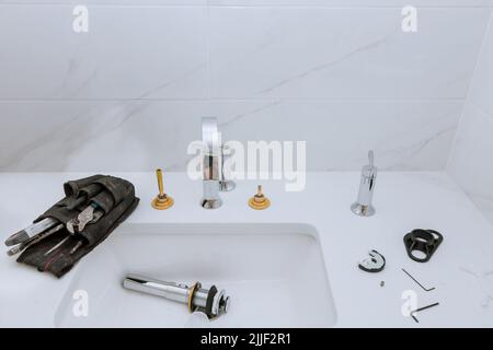 Als Teil seiner Arbeit montiert, installiert und justiert der Klempner den Wasserhahn im Badezimmer. Stockfoto