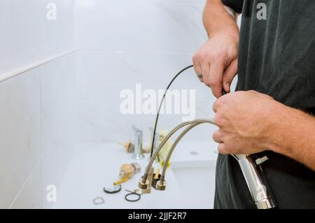 Als Klempner bei der Arbeit montiert und installiert er den Wasserhahn im Badezimmer Stockfoto