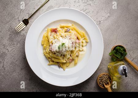 Italienische Pasta Penne-Sahnesauce mit Hackfleisch-Sauce und Parmesan-Käse in weißem Teller auf Textur-Tisch Stockfoto