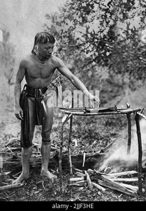 Ein Dayak-Mann aus Bornoe, der das Gift für seine Dartblowpipe mischt, wahrscheinlich aus dem saft von Antiaris toxicaria und Styrchnos nux-vomica; Bild veröffentlicht 1929. Stockfoto