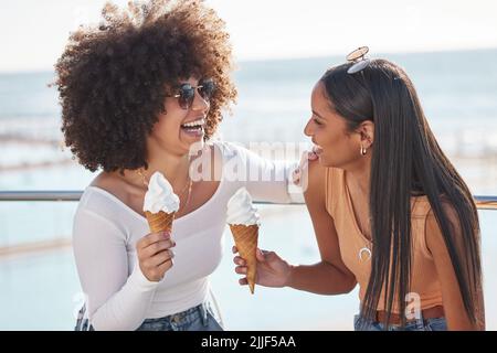 Die Schwesternschaft ist stark mit diesen beiden. Zwei junge Freunde genießen Eiskegel beim Abhängen an der Promenade. Stockfoto