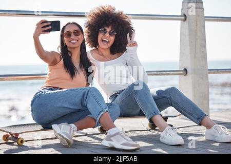 Beste Freunde bis zum Ende, besser halb so, zwei junge Freunde, die zusammen Selfies an der Promenade machen. Stockfoto