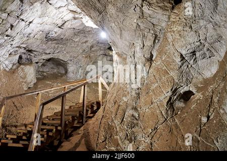 Alte Höhle mit gepflasterten Holztreppen und Beleuchtung. Wilde Natur und Orte Stockfoto