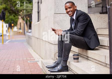 Machen Sie auf jeden Fall eine Mittagspause. Porträt eines hübschen jungen Geschäftsmannes, der während seiner Mittagspause seine Nachrichten absieht. Stockfoto