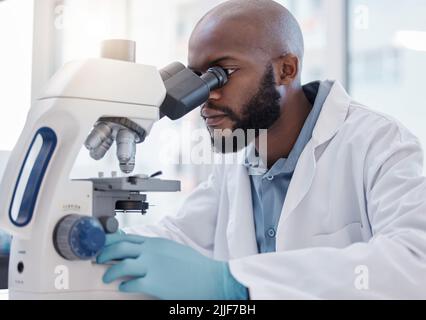 Erfolg ist eine Wissenschaft. Ein junger Wissenschaftler, der ein Mikroskop im Labor benutzt. Stockfoto