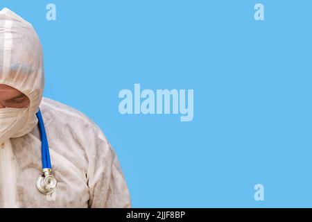 Arzt in Schutzanzug-Uniform mit Schutzbrille und medizinischer Gesichtsmaske auf einem Studio-blauen Hintergrund, Kopierraum Stockfoto