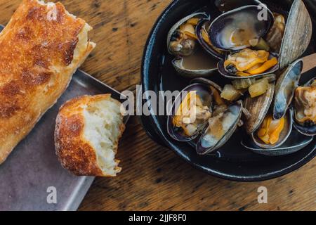 Muscheln in Brühschale mit knusprigem Brot Stockfoto