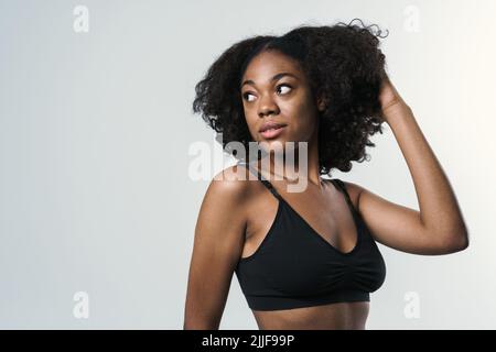 Junge schwarze Frau in Sportkleidung posiert und schaut isoliert auf weißem Hintergrund zur Seite Stockfoto