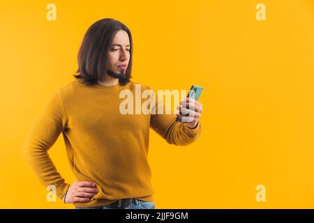 Ein hispanischer bärtiger Mann, der in ein Mobiltelefon schaut und eine Nachricht liest. Hochwertige Fotos Stockfoto