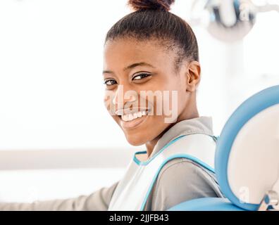 Noch nie war mein Lächeln schöner. Eine junge Frau, die in einem Zahnarztbüro auf die Behandlung wartet. Stockfoto