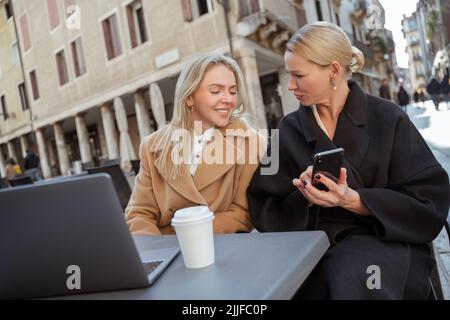 Zwei Frauen sitzen in einem Straßencafé Stockfoto