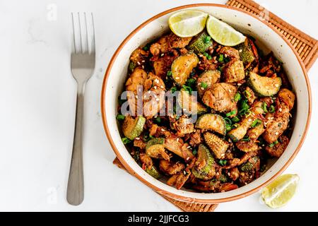 Gebratenes Huhn und Gemüse in einer Schüssel mit einer Gabel oben nach unten Foto, Healthy Asian Food Photography Stockfoto