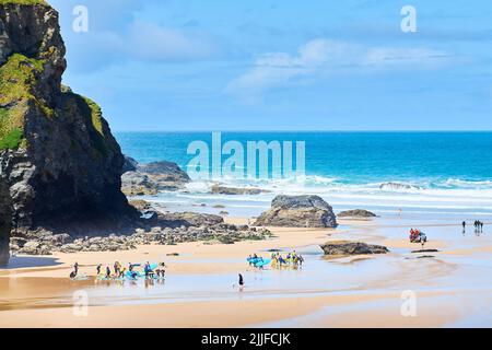 Am Strand von Mawgan Porth, Cornwall, England, schwängt eine Gruppe junger anfeigter Surfer. Stockfoto