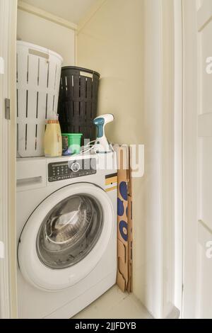 Moderne Toilettenspülung und Keramikwaschbecken, die an weiß gefliesten Wänden in der Nähe von Spiegel und Handtuch in der kleinen Toilette zu Hause installiert sind Stockfoto