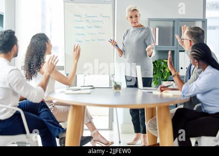 Möchte jemand sich für diese Aufgaben freiwillig melden. Eine reife Geschäftsfrau, die ihren Kollegen in einem Büro einen Vortrag gibt. Stockfoto