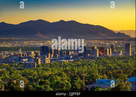 Skyline von Salt Lake City bei Sonnenuntergang mit Wasatch Mountains im Hintergrund, Utah Stockfoto