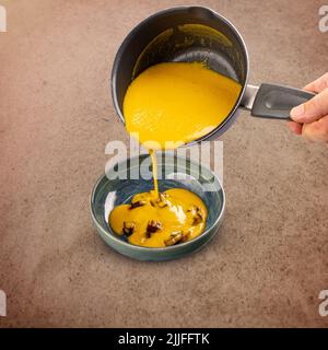 Karottensuppe, die in eine Schüssel über Rote-Bete-Würfel gegossen wird Stockfoto