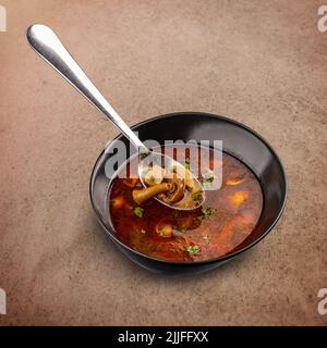 Köstliche Pilzsuppe mit Paprika in schwarzer Schüssel serviert Stockfoto