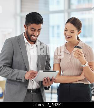 Ihre Arbeit hat sich stark verbessert. Ein Geschäftsmann und eine Geschäftsfrau sprechen, während sie ein digitales Tablet benutzen. Stockfoto