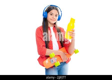 Teen Hipster Mädchen Skater mit Skateboard Wasserflasche und Kopfhörer auf isoliertem Hintergrund. Sommer Kinder Trend, urban Teenager-Stil. Stockfoto