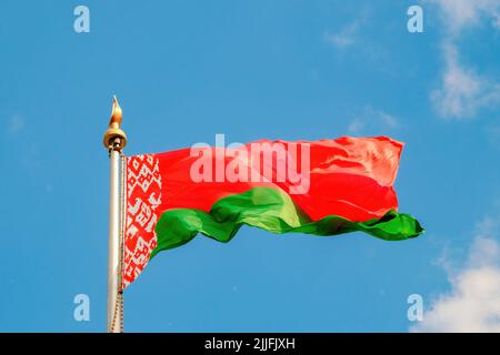 Die Flagge der Republik Belarus fliegt im Wind gegen den blauen Himmel. Nahaufnahme. Stockfoto