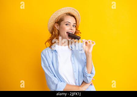 Portrait von fröhlichen lustigen Teenager-Mädchen genießt den Verzehr von kalten gefrorenen Dessert, isst köstliche Schokolade Eis, gelber Hintergrund. Stockfoto