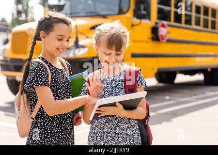 Entzückende Schulkinder, die zum Schulbus laufen Stockfoto