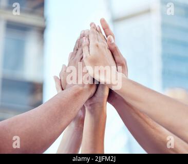 Gemeinsam können wir große Dinge tun. Eine Gruppe von unkenntlichen Menschen, die sich gegenseitig eine hohe fünf in der Stadt geben. Stockfoto