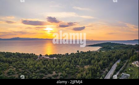 Die natürliche Schönheit des griechischen Pinienwaldes und des berühmten Glarokavos-Strandes und -Hafens bei Sonnenuntergang aus der Vogelperspektive. Sommerferien Konzept. Hochwertige Fotos Stockfoto
