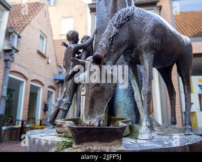 Die Skulptur eines Pferdes, das Wasser trinkt, vor einem hübschen Paar in einer Straße in Brügge, Belgien. Stockfoto