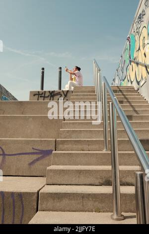 Eine vertikale Aufnahme einer Frau, die auf einer Treppe sitzt Stockfoto