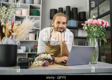 Floristin bärtiger Mann mit Laptop. GewächshausArbeiter, männlicher