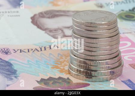 Stapel ukrainischer Hrivnya-Münzen, die auf zweihundert ukrainischen Hrivnya-Banknoten stehen Stockfoto