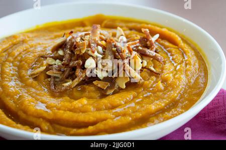 Kürbiscreme und Walnüsse in einer weißen Schüssel, serviert zu Hause. Stockfoto