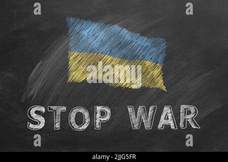 Nationalflagge der Ukraine und Schriftzug STOPPEN DEN KRIEG, handgezeichnet mit Kreide auf der Tafel. Flagge winkt im Wind. Stehe mit der Ukraine Stockfoto