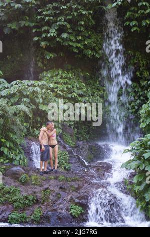 Ein Touristenpaar steht in der Nähe des Benang Kelambu Wasserfalls in Lombok, Indonesien Stockfoto