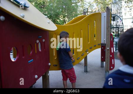 Mobbing auf dem Spielplatz, Junge steht allein, während Kind schaut auf in den Vordergrund, Paris, Frankreich Stockfoto