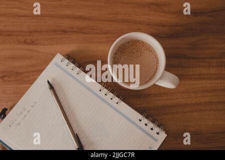 Flacher Holztisch mit Notizbuch und Kaffeetasse Stockfoto