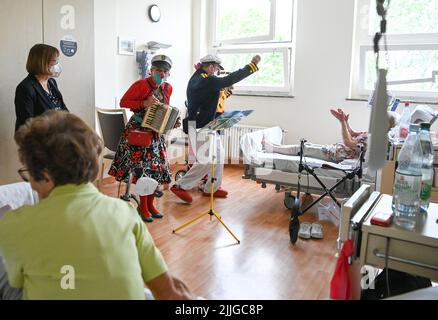 Potsdam, Deutschland. 26.. Juli 2022. Clowns Beta (l) und Widu besuchen Senioren in der Ernst von Bergmann Klinik. Hinzu kommt Ursula Nonnemacher (l, Bündnis 90/die Grünen), Brandenburgs Gesundheitsministerin. Die Clownsbesuche wurden speziell für körperlich oder geistig beeinträchtigte Patienten entwickelt und tragen zur Verbesserung ihrer Lebensqualität bei. Quelle: Jens Kalaene/dpa/Alamy Live News Stockfoto