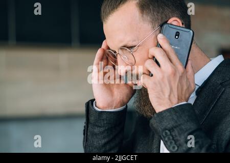 Mann, der mobil spricht, Kopfschmerzen beim Telefongespräch Stockfoto