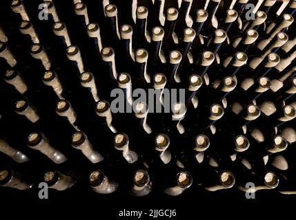 Weinkeller bei schwachem Licht Innenaufnahme. Weinglas Flaschenhälse mit Korken Hintergründe mit einer Sammlung von Weinflaschen. Geldanlage und Weinherstellung Stockfoto