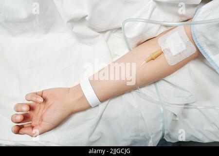 Von oben gesehen Aufnahme einer nicht erkennbaren weiblichen Patientin, die Medikamentenflüssigkeiten über die IV-Leitung erhielt Stockfoto