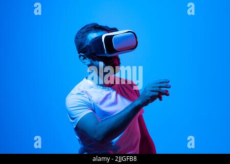 Ein junger Mann mit VR-Headset und einem Freund im Metaverse spricht während eines Spiels. Stockfoto