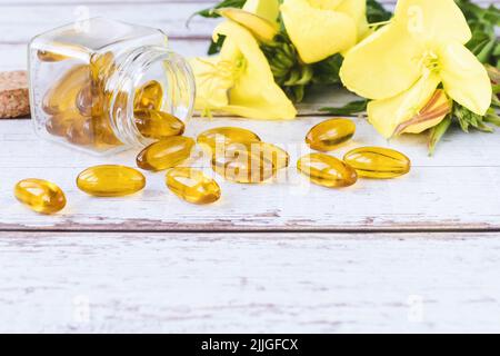 Softgels mit Nachtkerzenöl, Kräuterarzneimittel, Blüten der Primrose-Pflanze, Kopierraum Stockfoto