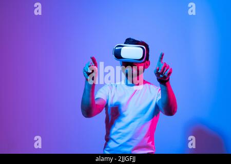Bild eines jungen Mannes, der ein Virtual-Reality-Headset trägt und online ein Videospiel spielt. Technologie der Zukunft. Stockfoto