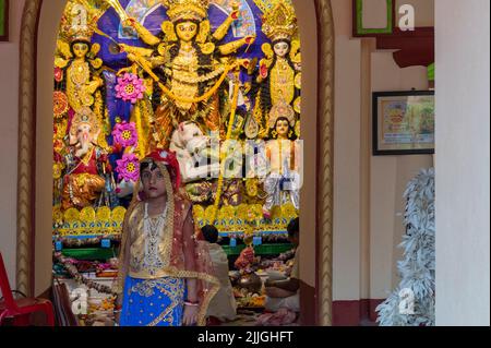 Howrah, Indien -26.. Oktober 2020 : Bengalisches Mädchen Kind posiert mit Göttin Durga im Hintergrund, im Altersheim dekoriert. Durga Puja. Stockfoto