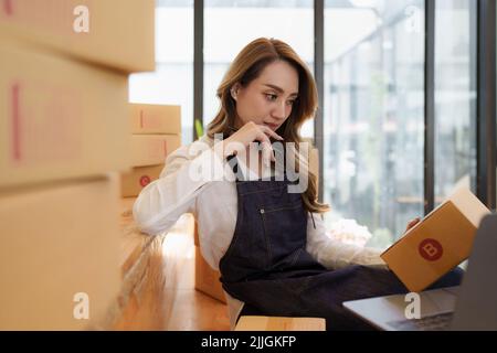 Junge asiatische Frau im Lager zur Lieferung an Unternehmer Eigentümer SME. Business digital online KMU Kleinunternehmen und Online-Shop. Stockfoto