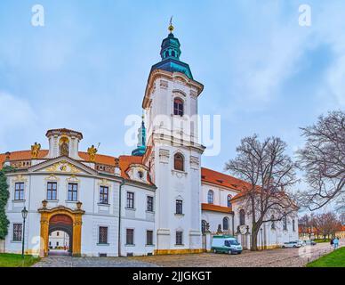 Der hohe barocke Glockenturm und die geschnitzten Steinskulpturen der Basilika Mariä Himmelfahrt im Kloster Strahov, Prag, Tschechische Republik Stockfoto